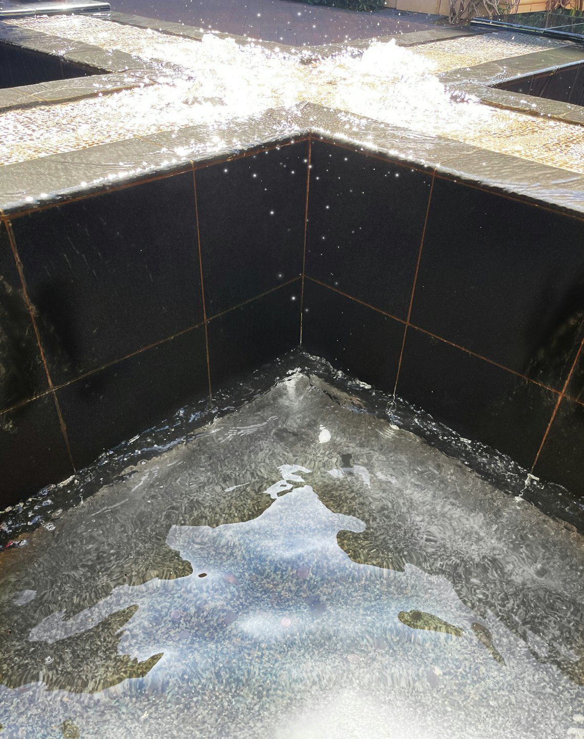 Modern black tiled water fountain with cascading water.